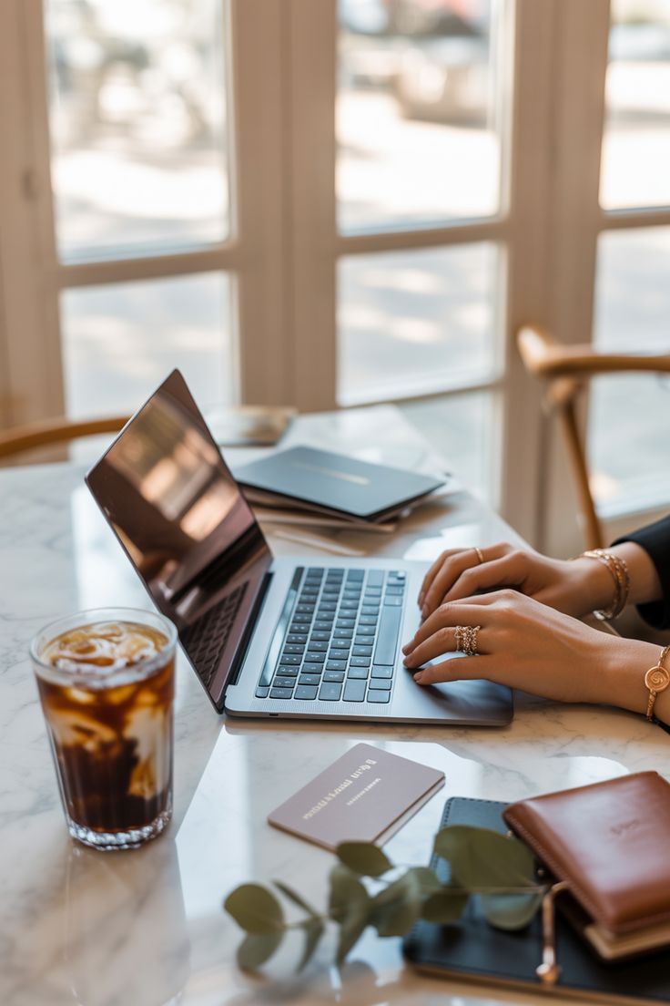 Personne travaillant sur un ordinateur portable, carnet et café à côté