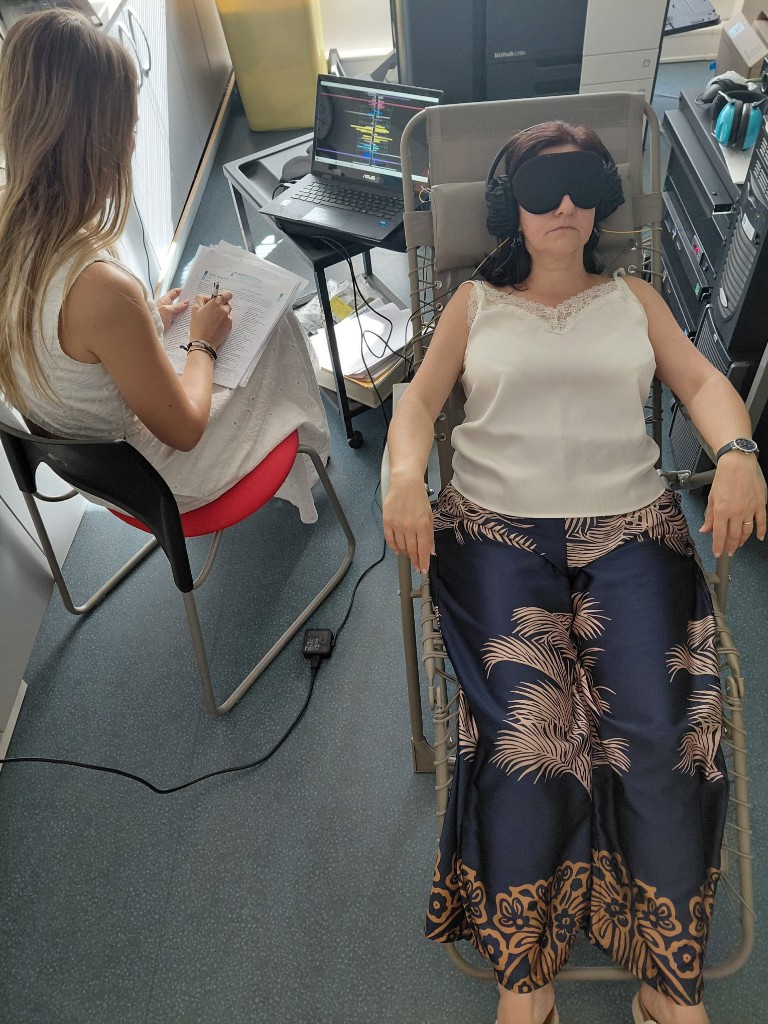 Séance de neurofeedback : cliente allongée avec casque et capteurs, praticienne prenant des notes.